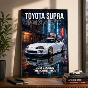 May include: A framed poster showing a white Toyota Supra with gold wheels, reflected in a wet street. The poster includes the text "TOYOTA SUPRA" and "JDM LEGEND THE ICONIC MKIV". Japanese text and neon signs are also visible.