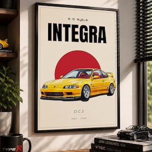 Puede incluir: Póster enmarcado con una ilustración de un coche Honda Integra DC2 amarillo y un sol rojo. El póster incluye el texto "HONDA INTEGRA" y los años "1997-2000". Una taza negra con "TYPE R" está en el escritorio.
