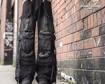 May include: Black denim cargo pants with multiple pockets and distressed details. The pants have a wide leg design and are styled with black boots. The image includes the text "AbieDazzling" on the right side.