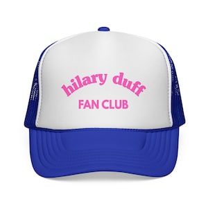 Puede incluir: Gorra de camionero azul y blanca con el texto "hilary duff FAN CLUB" en rosa. La gorra tiene una visera azul y un panel frontal blanco con el texto. Los laterales y la parte trasera de la gorra son de malla azul.