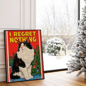 Könnte beinhalten: Ein rechteckiges gerahmtes Wandbild mit einer schwarz-weißen, langhaarigen Katze, die vor einem grünen Weihnachtsbaum sitzt. Der Hintergrund ist leuchtend rot und trägt oben den gelben Schriftzug I REGRET NOTHING in fetten Großbuchstaben.