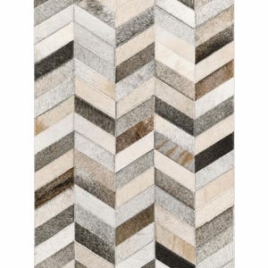 May include: A rectangular area rug featuring a chevron pattern composed of stitched cowhide panels. The rug displays a palette of white, cream, beige, gray, and dark brown tones, with each individual panel showcasing natural hair-on-hide textures.