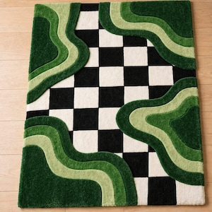 May include: A rectangular rug featuring a black and white chequered pattern, with layered, wavy shapes in varying shades of green. The rug has a textured, plush finish, enhancing the visual appeal and depth of the design.