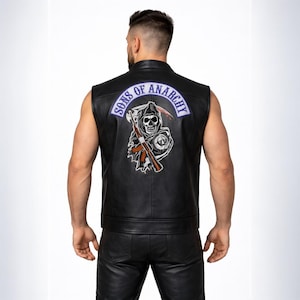 Può includere: Gilet in pelle nera con toppa Sons of Anarchy sul retro. La toppa presenta un'immagine di un mietitore con falce e fucile, e le parole "Sons of Anarchy" in un design ad arco blu e bianco.