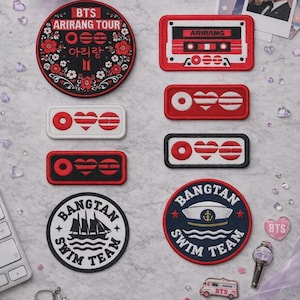 Może przedstawiać: Kolekcja haftowanych naszywek z okrągłymi wzorami BTS Arirang Tour, prostokątnymi motywami kaset magnetofonowych oraz okrągłymi emblematami Bangtan Swim Team z grafikami statku i czapki marynarskiej, a także małymi naszywkami w kształcie serca i autobusu.