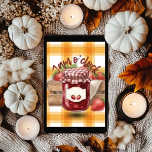 Op de afbeelding: Een tablet toont een digitale illustratie van een jam pot met de tekst "Jam o'clock". De pot is gevuld met rode jam en heeft een geruite deksel. Witte pompoenen, kaarsen en herfstbladeren omringen de tablet.