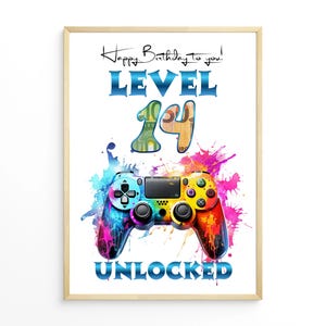 May include: A framed print with a colorful design. The words "Happy Birthday to you! LEVEL 14 UNLOCKED" are displayed above a vibrant game controller illustration. The controller is painted with blue, yellow, and red hues.
