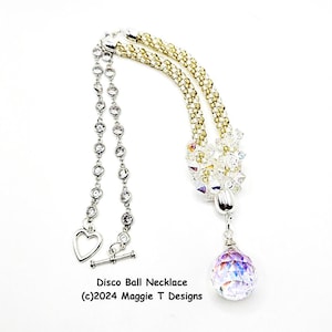 Pode incluir: Um colar prateado com detalhes em cristal transparente e um fecho em forma de coração. O colar apresenta um aglomerado de cristais transparentes e um grande pendente de bola de discoteca iridescente. O texto "Disco Ball Necklace" é visível.