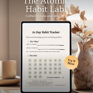 Pode incluir: Um tablet digital exibindo um rastreador de hábitos de 31 dias, parte do "The Atomic Habit Lab". A tela mostra uma grade para rastreamento de hábitos e solicitações para definir metas. Um botão "Try It Now" é visível. Um vaso com flores ao fundo.