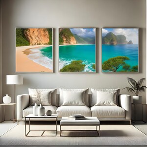 May include: Three framed landscape art prints showing tropical beach scenes. Each print features a sandy beach, turquoise water, and cliffs. The artwork is displayed above a white sofa in a living room setting.