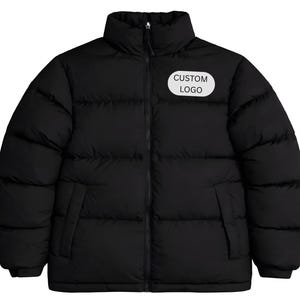 Könnte beinhalten: Schwarze Steppjacke mit hohem Kragen und Reißverschluss. Die Jacke hat zwei Seitentaschen und einen weißen ovalen Aufnäher mit der Aufschrift "CUSTOM LOGO". Dieser Wintermantel ist auf Wärme und Stil ausgelegt.
