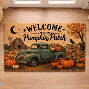 May include: A rectangular doormat featuring a teal vintage truck in a pumpkin patch with a barn, a crescent moon, and a wooden sign reading PUMPKINS, HAYRIDES, APPLE CIDER. The text WELCOME to our Pumpkin Patch is printed in black script.
