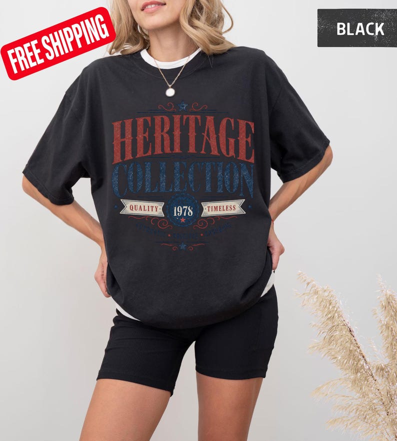 May include: Black t-shirt with the text "HERITAGE COLLECTION" in red and blue. The shirt also features the text "QUALITY 1978 TIMELESS". The shirt is worn with black shorts.