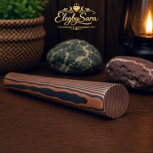 May include: A cylindrical object featuring a layered pattern of alternating copper and black bands. The surface displays a distinct striped texture running along the length of the cylinder, with a flat circular end visible in the foreground.
