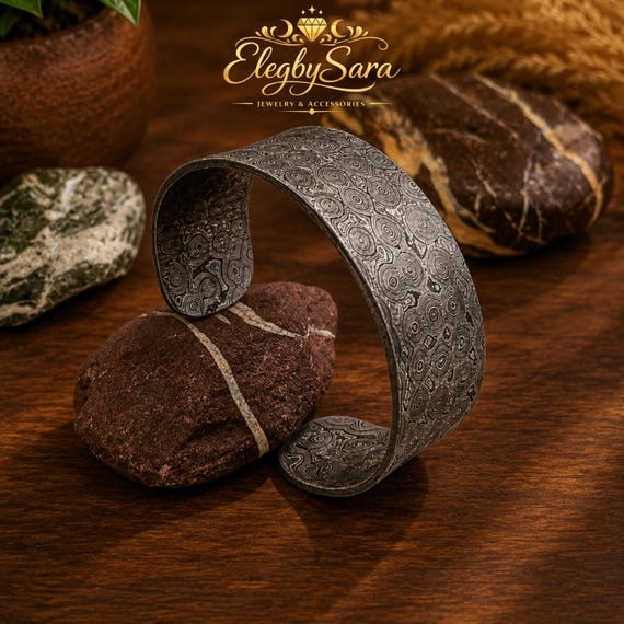 A genuinely hand-forged Damascus steel cuff with a raindrop pattern — the kind of wearable metalwork that looks like it came from a blacksmith's forge, not a factory.