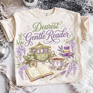May include: Cream-colored t-shirt with a whimsical design featuring a horse-drawn carriage, teacup, open book, and the text "Dearest Gentle Reader." The design includes lavender and purple floral elements.