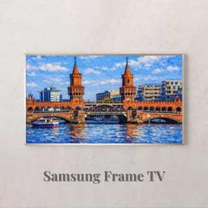 May include: A framed print depicting a bridge over a river, featuring two tall towers and a boat. The artwork is in a painterly style, with blue water and sky. The text "Samsung Frame TV" is at the bottom.