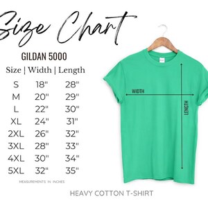 Op de afbeelding: Maattabel voor een Gildan 5000 heavy cotton t-shirt. De tabel toont de afmetingen in inches voor maten S tot 5XL. Een groen t-shirt hangt aan een houten hanger, met breedte- en lengte-indicatoren.