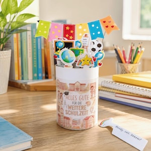 Puede incluir: Un recipiente cilíndrico blanco decorado con ilustraciones escolares y el texto en alemán "ALLES GUTE FÜR DIE WEITERE SCHULZEIT". Está rematado con banderines coloridos y varios recortes relacionados con la escuela como globos y un balón.
