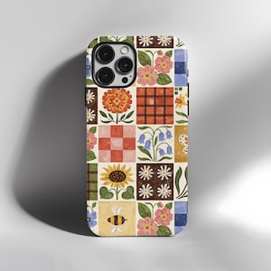 Può includere: Custodia per telefono colorata con un design patchwork. Il motivo comprende fiori, api e motivi geometrici. La custodia ha un bordo nero e un ritaglio per la fotocamera. Il design è disposto a griglia.