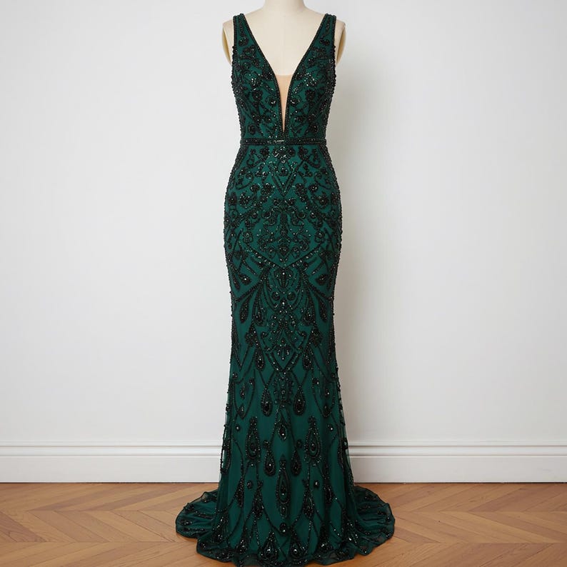 May include: A dark green, floor-length, sleeveless gown with a plunging V-neckline and intricate beading throughout.