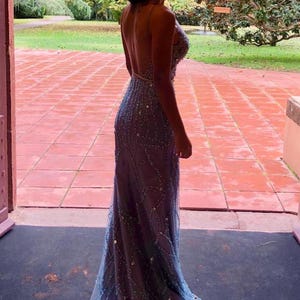 May include: A woman wearing a long, light blue, beaded, backless gown with a mermaid silhouette.