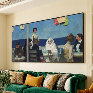 Puede incluir: Una pintura grande enmarcada que representa una escena de café con figuras, incluido un payaso, sentadas en mesas. La obra de arte presenta un fondo de cielo azul y se exhibe sobre un sofá de terciopelo verde con cojines decorativos.