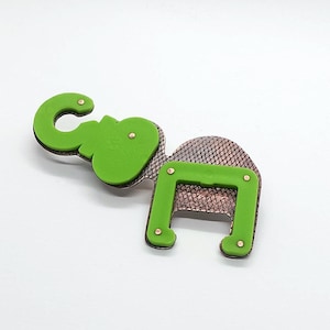 Puede incluir: Un abridor de botellas caprichoso con forma de elefante y nota musical. La cabeza del elefante verde y la sección de la nota están unidas a un cuerpo texturizado de color cobre con pequeños remaches dorados. Diseño divertido y artístico.