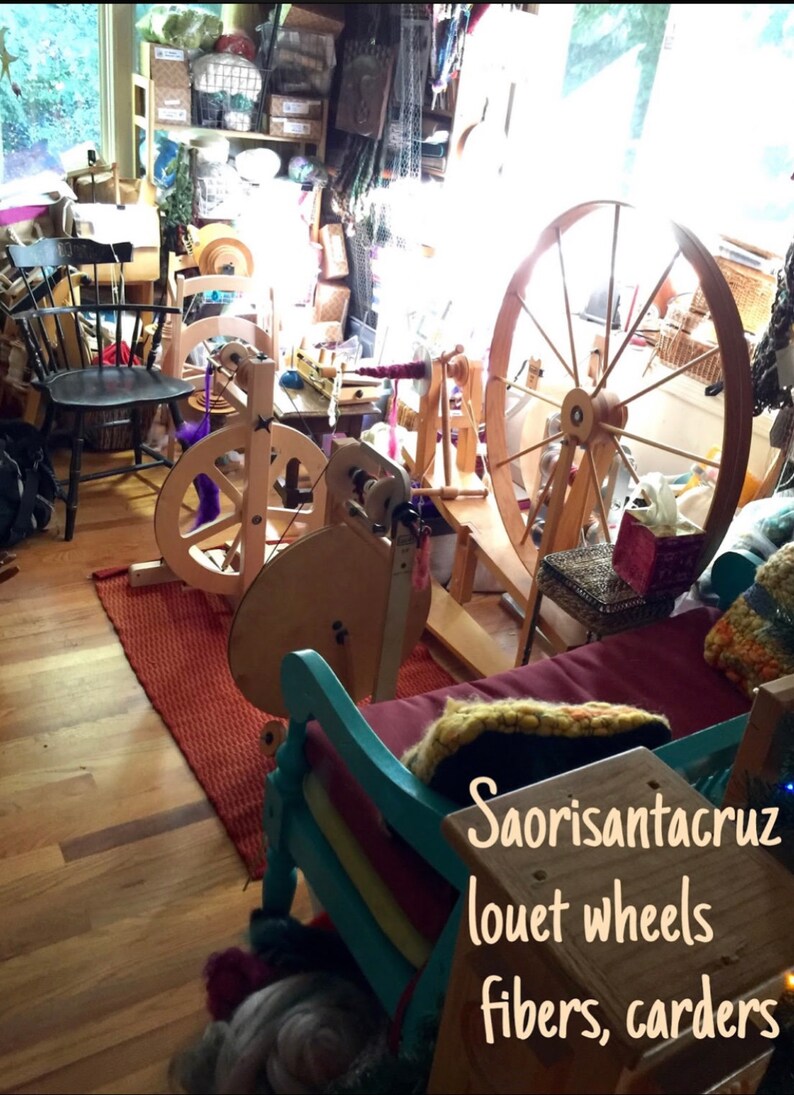 Puede incluir: Una habitaci&oacute;n llena de ruecas, cardas y fibras. La habitaci&oacute;n est&aacute; llena de luz natural y tiene un ambiente r&uacute;stico. El texto "Saorisantacruz louet wheels fibers, carders" es visible en la imagen.