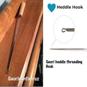 May include: A Saori heddle threading hook with a wooden handle and a thin, metal shaft. The hook is designed for weaving and features a small, curved end for threading. The image also includes the text "Heddle Hook" and "Saori heddle threading Hook".