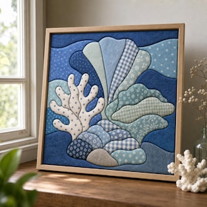 May include: A square fabric wall art piece in a light wooden frame, featuring a layered textile collage of an underwater scene. The design includes various shades of blue and white fabric patches with floral, gingham, and polka dot patterns.