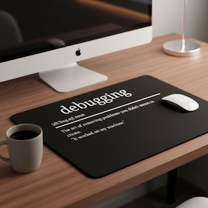May include: Black rectangular mouse mat with the word "debugging" in white, along with a definition. A white mouse and a coffee mug are on the wooden desk. A computer monitor is in the background.