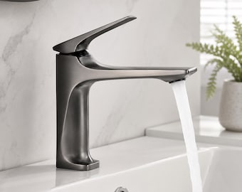 Puede incluir: Un grifo de baño de metal gris oscuro mate con una manija de palanca única en la parte superior. El grifo tiene una silueta curva y moderna y está montado sobre un lavabo blanco. Un flujo constante de agua sale del caño hacia el lavabo.