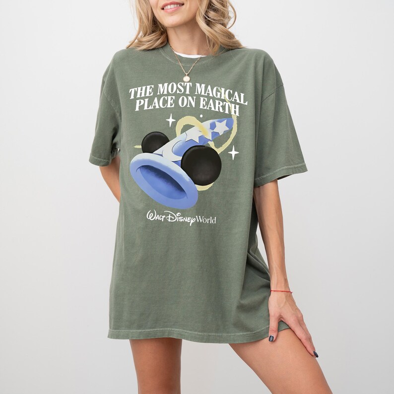 May include: Olive green t-shirt with the text "THE MOST MAGICAL PLACE ON EARTH" and a graphic of a blue and black wizard hat with stars. The Walt Disney World logo is below the graphic.