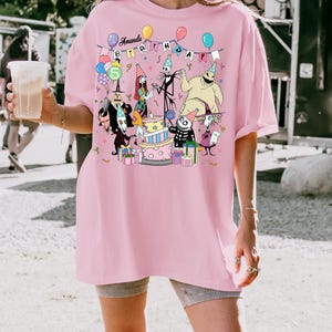 May include: A light pink t-shirt with a colourful graphic of characters from The Nightmare Before Christmas celebrating a birthday. The text "Amanda Birthday" is displayed above the characters. A large number "5" is also visible.