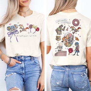 May include: A cream-colored t-shirt featuring Zootopia characters and icons. The front displays mouse ears and the text "You can be anything you wish to be." The back shows a collage of characters, a badge, a donut, and a carrot graphic.