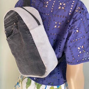Mochila mini de jeans bicolor com 4 bolsos forrados e alça única, feita com materiais reciclados.