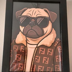 May include: Framed art print of a pug wearing sunglasses and a brown jacket with a repeating pattern. The pug has a tan face and brown ears, set against a black background.
