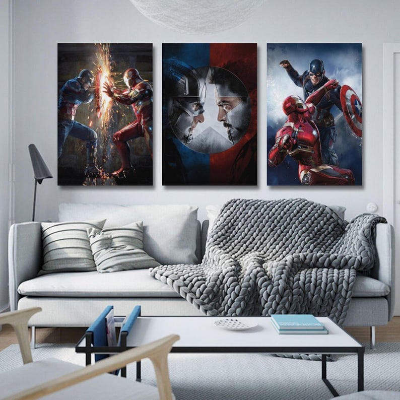 May include: Three canvas art prints featuring superhero battles. The first shows Captain America and Iron Man clashing, the second features their faces split by a shield, and the third shows them in action. The artwork is displayed above a white sofa.