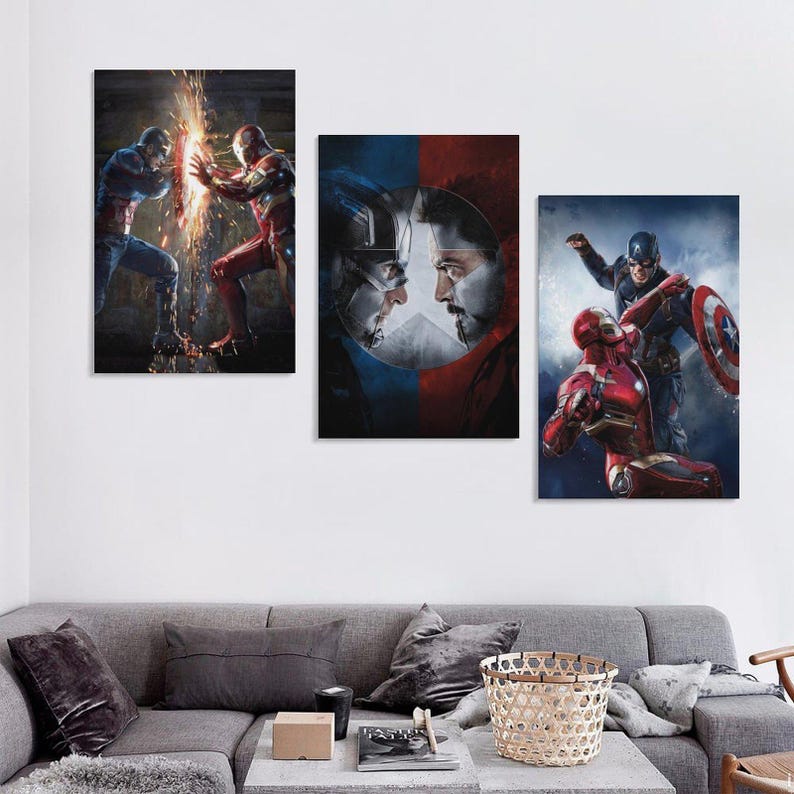 May include: A triptych of framed canvas prints depicting Marvel superheroes. One shows Captain America and Iron Man in conflict, another features their faces, and the third shows them in action. The prints are displayed above a grey sofa.