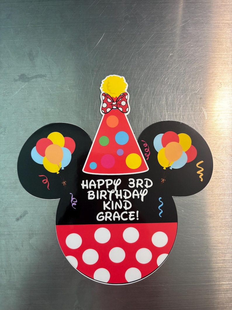 May include: A die-cut sign shaped like a mouse head with black ears, a red polka-dot base, and a party hat on top. The sign features colorful balloons, confetti, and the text "HAPPY 3RD BIRTHDAY KIND GRACE!" printed in white on the black center section.