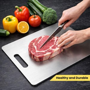May include: A stainless steel cutting board with a raw steak being sliced. Fresh vegetables, including bell peppers, tomatoes, broccoli, and cucumbers, are arranged around the board. The text "Healthy and Durable" is in a yellow banner.
