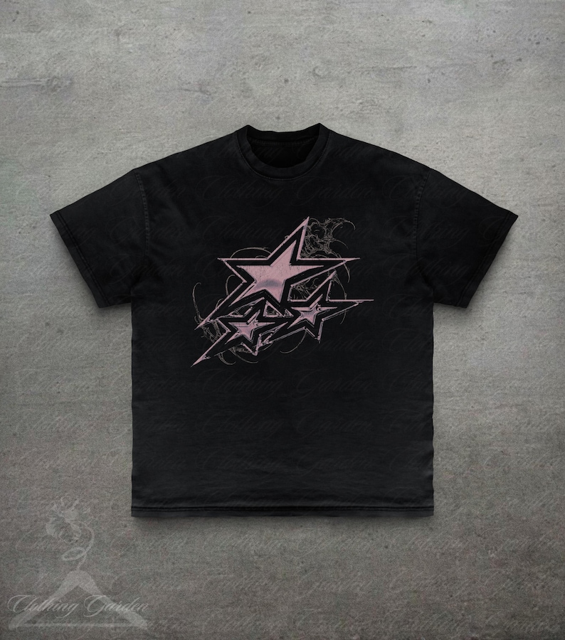 Op de afbeelding: Zwart t-shirt met een roze sterrenontwerp. De afbeelding toont meerdere sterren met een distressed, grunge-esthetiek. Het shirt heeft een klassieke ronde hals en korte mouwen, geschikt voor casual wear.