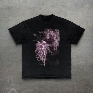 May include: Black t-shirt with a gothic fairy illustration in purple and white. The design features detailed imagery and a dark, ethereal style. The shirt has a classic crew neck and short sleeves. The t-shirt is made of a soft material.