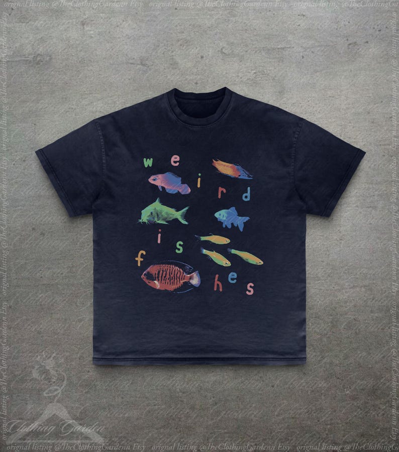 Puede incluir: Camiseta azul marino con ilustraciones coloridas de varios peces y el texto "weird fishes" en una fuente l&uacute;dica. El dise&ntilde;o incluye peces en tonos azules, naranjas, verdes y amarillos.