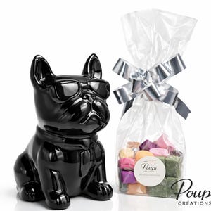 Peut inclure: Une figurine de bouledogue noir brillant avec des lunettes de soleil est à côté d'un sac en cellophane noué avec un nœud argenté. Le sac contient des articles carrés colorés. Le sac porte l'inscription "Poupi Créations".
