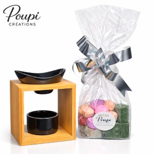 Peut inclure: Un diffuseur d'huiles essentielles en bois avec des coupelles en céramique noire. Un sac en cellophane noué d'un ruban argenté contient des fondants parfumés colorés. Le sac porte l'inscription "Poupi Créations".