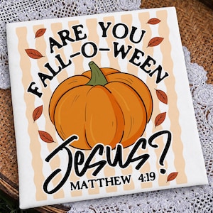 Può includere: Un tessuto quadrato bianco con una zucca arancione centrale dal picciolo verde. Il testo ARE YOU FALL-O-WEEN JESUS? MATTHEW 4:19 è scritto in nero. Lo sfondo presenta strisce ondulate verticali color arancio chiaro e foglie autunnali marroni sparse.