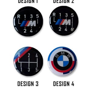 Puede incluir: Cuatro diseños negros y circulares de pomo de palanca de cambios para coche. Los diseños 1 y 2 presentan el logotipo de BMW y el patrón de cambio de marchas. El diseño 3 tiene un patrón de cambio de marchas con rayas azules, rojas y blancas. El diseño 4 tiene el logotipo de BMW.