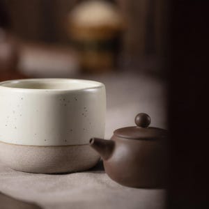 Peut inclure: Une tasse en céramique blanche avec une anse noire et le texte "But First, Coffee" en noir gras. La tasse est posée sur une surface en bois. La tasse mesure environ 10 cm de haut.